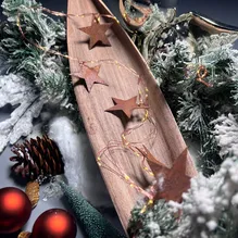 Eine Lichterkette mit Weihnachtssternen aus Cortenstahl auf einer Holzschale