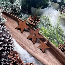 Drei Weihnachtssterne aus Cortenstahl auf einem dekorierten Tisch