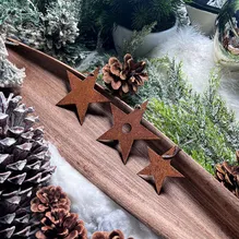 Drei Weihnachtssterne aus Cortenstahl auf einem dekorierten Tisch